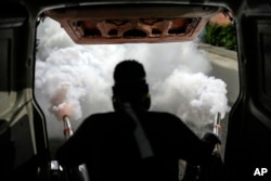 A worker fumigates a neighborhood against dengue-promoting mosquitoes, in Caracas, Venezuela, Tuesday, Dec. 12, 2023. (AP Photo/Matias Delacroix)