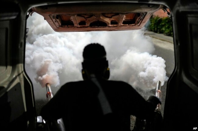 A worker fumigates a neighborhood against dengue-promoting mosquitoes, in Caracas, Venezuela, Tuesday, Dec. 12, 2023. (AP Photo/Matias Delacroix)