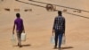 Sudanese men carry bottles of water back to their home in Khartoum on May 25, 2023.