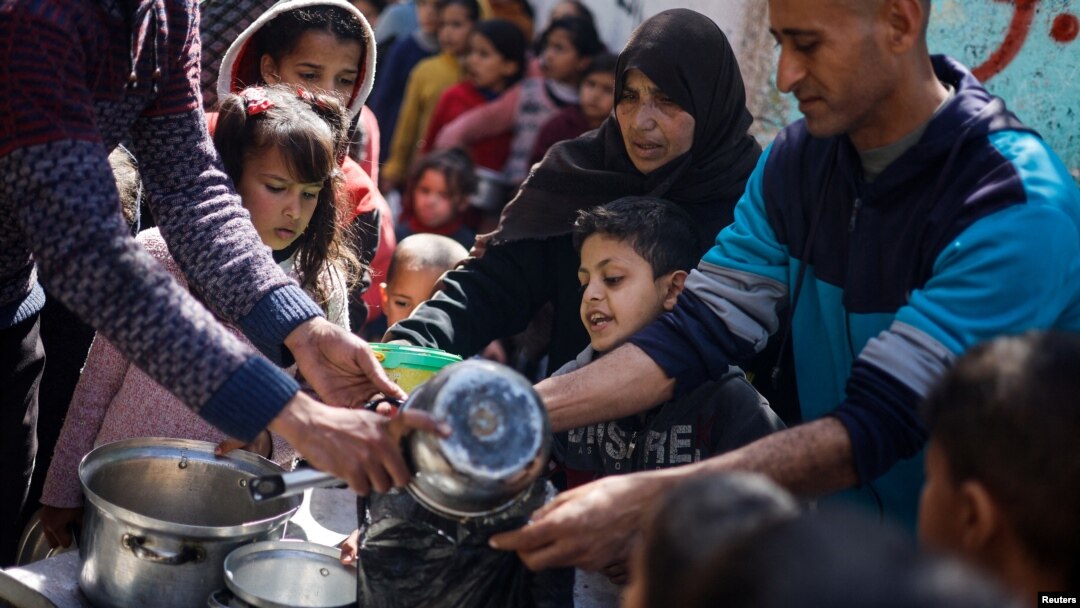 Palestinian children wait to receive food prepared by a charity kitchen amid shortages of food supplies, as the conflict between Israel and Hamas continues, in Rafah, in the southern Gaza Strip, March 5, 2024.