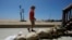 Seal Beach resident Tom Ostrom walks past a home protected with sandbags in Seal Beach, California, Aug. 18, 2023. Hurricane Hilary is churning off Mexico's Pacific coast as a powerful Category 4 storm threatening to unleash torrential rains.