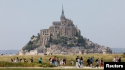 People walk past France's Mont-Saint-Michel during the French President's two-day visit in Normandy, in Le Mont-Saint-Michel, June 5, 2023.