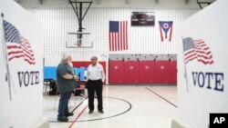 Voter Marty Savage stops to talk with poll worker Tom Rodgers in the Thornville Middle School gymnasium, in Thornville, Ohio, Aug. 8, 2023.