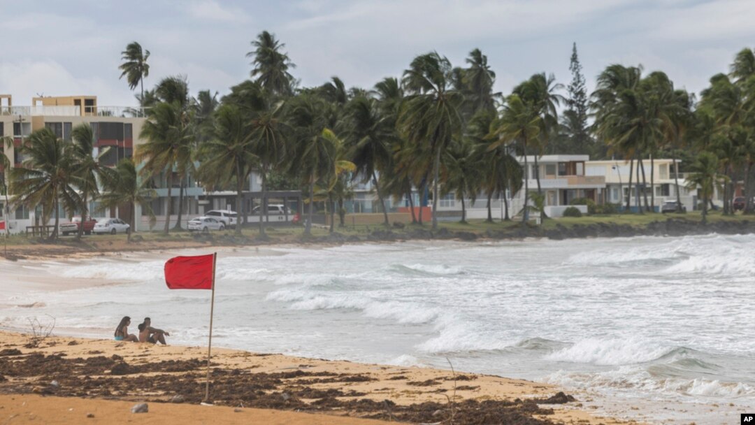 Tourists sit on La Pared beach as Tropical Storm Ernesto passes by Luquillo, Puerto Rico, Aug. 13, 2024.