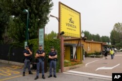 Polisi berjaga di luar Camping Hu, tempat para penumpang bus menginap, di Mestre, dekat kota Venesia, Italia, Rabu, 4 Oktober 2023. Bus tersebut jatuh dari jalan layang, Selasa malam, menewaskan banyak orang. (AP/Antonio Calanni)