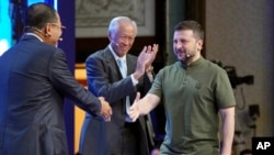 Ukraine's President Volodymyr Zelenskyy, right, shakes hand with Malaysian Defense Minister Mohamed Khaled Nordin, left, and Singaporean Defense Minister Ng Eng Hen at the 21st Shangri-La Dialogue summit at the Shangri-La Hotel in Singapore, June 2, 2024.
