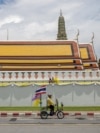 Seorang pendukung kerajaan mengendarai sepedanya yang berhiaskan bendera melewati Grand Palace pada peringatan 70 tahun Raja Thailand Maha Vajiralongkorn di Bangkok pada 28 Juli 2022. (Foto: AFP)