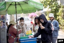 Orang-orang membeli es krim dari pedagang kaki lima saat kondisi gelombang panas melanda Bangkok.