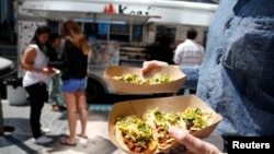 FILE - People buy tacos from a Korean food truck in Los Angeles, California.