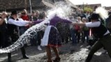 A woman dressed in traditional clothes reacts as men throw water at her during a traditional Easter celebration in Holloko, Hungary, April 1, 2024.
