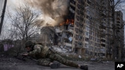 A Ukrainian police officer takes cover in front of a burning building that was hit in a Russian airstrike in Avdiivka, Ukraine, March 17, 2023.