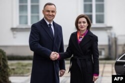 Polish President Andrzej Duda greets the President of Moldova Maia Sandu upon her arrival in front of the Belvedere Palace in Warsaw, Feb. 22, 2023.
