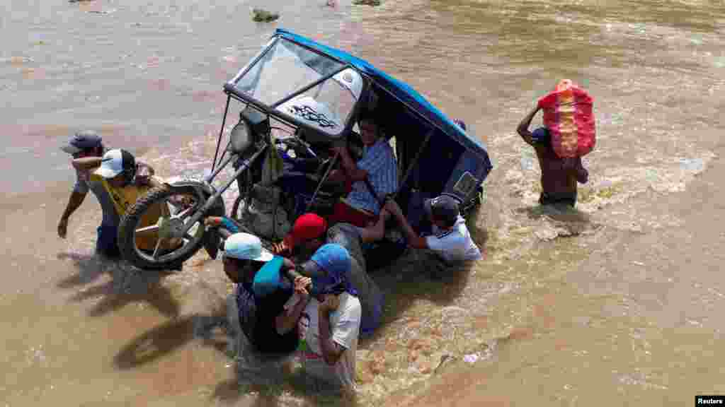 Warga berusaha menarik ojek melintasi aliran sungai yang meluap akibat pengaruh langsung dari Topan Yaku, di kota Piura, Peru. (Reuters)&nbsp;