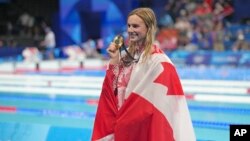 FILE - Canada's Summer Mcintosh celebrates winning the gold medal in the women's 200-meter individual medley at the Summer Olympics in Nanterre, France, Aug. 3, 2024.