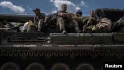 Ukrainian servicemen sit atop a military vehicle, amid Russia's attack on Ukraine, near the Russian border in Ukraine's Sumy region, Aug. 11, 2024.