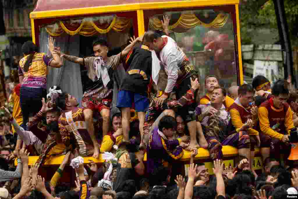 Filipino devotees fight to get on the cart that carries the statue of the Black Nazarene during its yearly procession in Manila.