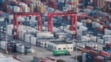 FILE - A cargo truck drives amid stacked shipping containers at the Yangshan port in Shanghai, China, March 29, 2018.