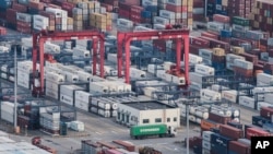 Sebuah truk kargo tampak berjalan di antara kumpulan kontainer di pelabuhan Yangshan di Shanghai, China, pada 29 Maret 2018. (Foto: AP)