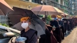Para biarawati Buddha mengumpulkan sedekah dengan kepala ditutupi handuk dan payung untuk berlindung dari sinar matahari saat gelombang panas melanda Yangon pada 24 April 2023. (Foto: AFP)