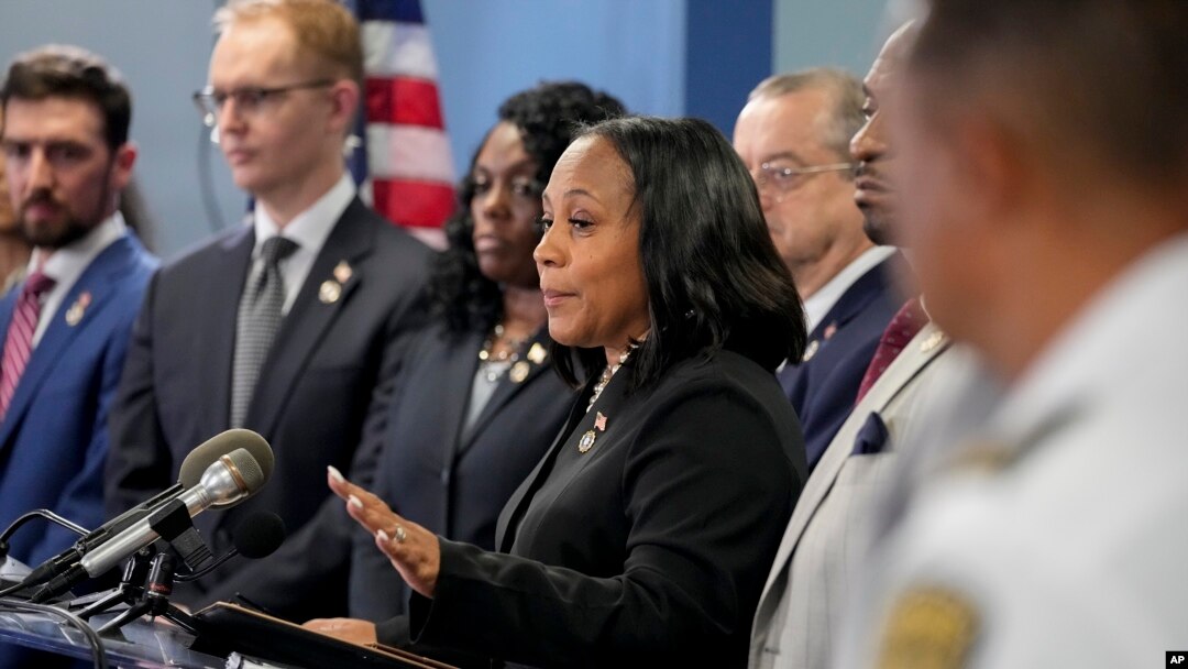Georgia eyaleti Fulton İlçesi Bölge Savcısı Fani Willis (ortada) eski Başkan Donald Trump hakkındaki dördüncü iddianameyi düzenlediği basın toplantısında açıkladı. 