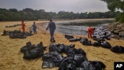Workers clean an oil spill along Sentosa's Tanjong Beach area in Singapore, June 16, 2024.