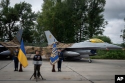 El presidente de Ucrania, Volodymyr Zelenskyy, habla con motivo del Día de las Fuerzas Aéreas frente a los aviones de combate F-16 de la Fuerza Aérea de Ucrania en un lugar no revelado en Ucrania, el domingo 4 de agosto de 2024.