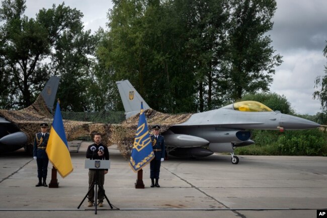 El presidente de Ucrania, Volodymyr Zelenskyy, habla con motivo del Día de las Fuerzas Aéreas frente a los aviones de combate F-16 de la Fuerza Aérea de Ucrania en un lugar no revelado en Ucrania, el domingo 4 de agosto de 2024.