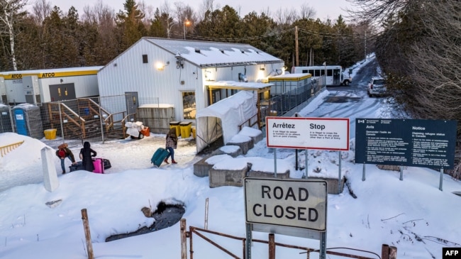 FILE - This aerial view shows migrants arriving at the Roxham Road border crossing in Roxham, Quebec, on March 3, 2023. (Photo by Sebastien ST-JEAN / AFP)