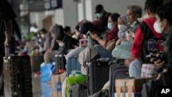 Para pemudik duduk di Stasiun Senen, Jakarta, menanti kereta api yang akan membawa mereka pulang ke kampung halaman mereka, 28 April 2022. (AP/Tatan Syuflana)