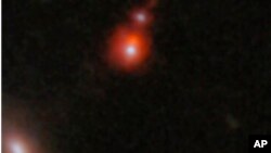 This image released by NASA shows the ZS7 galaxy system, revealing the ionized hydrogen emission in orange and the doubly ionized oxygen emission in dark red. 