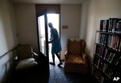 FILE - Janet Arnett looks out from the balcony of her Baltimore apartment on July 3, 2012, as she waits for power to be restored after storms knocked out power. Authorities are concerned about the growing impact of stuffy conditions and generator exhaust.