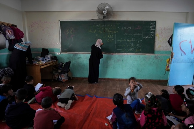 Manal Al Buhaisi works with children at a makeshift class in Deir al Balah, on Sunday, April 21, 2024. (AP Photo/Abdel Kareen Hana)