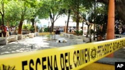 ARCHIVO - En esta fotografía de archivo del 10 de marzo de 2015, el cuerpo cubierto del un periodista yace en el suelo en el parque central de Mazatenango, Guatemala. 