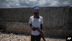 Un pandillero armado, con el rostro cubierto con pañuelo y lentes oscuros, posa para una foto en el barrio marginal Cite Soleil de Port-au-Prince, Haití, el jueves 20 de abril de 2023.