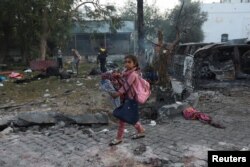 Una niña con sus pertenencias camina por la zona del hospital Al-Ahli donde cientos de palestinos murieron en una explosión en la ciudad de Gaza, el 18 de octubre de 2023.