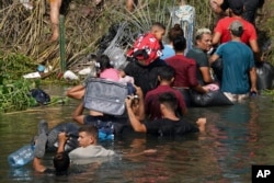 FILE - Venezuelan migrant Luis Parra, third right, joins other migrants crossing the Rio Grande river, seen from Matamoros, Mexico, May 10, 2023.