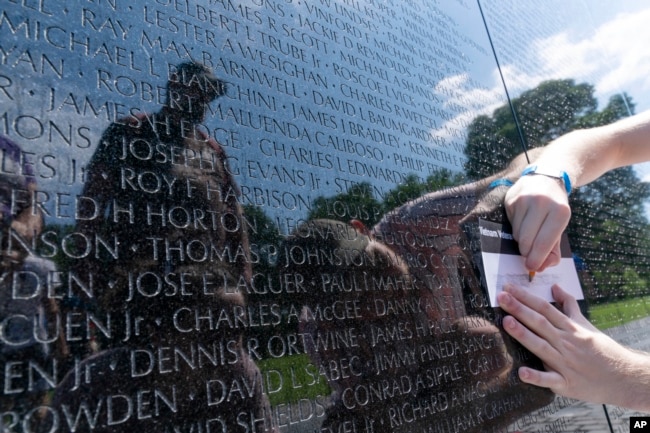 FILE - A visitor makes a rubbing of the name of a fallen soldiers at Vietnam Veterans Memorial on May 29, 2022. (AP Photo/Jose Luis Magana)