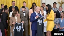 U.S. President Joe Biden is presented with a team jersey by Las Vegas Aces star A'ja Wilson while Vice President Kamala Harris is presented with a jersey by Chelsea Gray during a celebration of the 2023 WNBA champions at the White House on May 9, 2024.