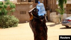 A woman carries a gallon of water during clashes between the paramilitary Rapid Support Forces and the army in Khartoum North, Sudan, April 22, 2023.