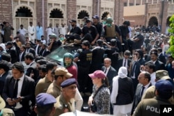 FILE - Security escorts a vehicle carrying Pakistan's former Prime Minister Imran Khan and his wife, Bushra Bibi, after their court appearance in Lahore, Pakistan, May 15, 2023.