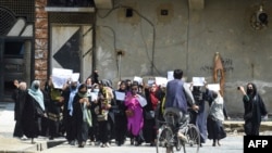 FILE - Afghan women hold placards as they march to protest in Kabul, April 29, 2023, to voice opposition to foreign nations formally recognizing the Taliban government ahead of a U.N. summit.