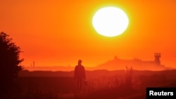 FILE - A migrant walks back to his makeshift camp at sunrise after a failed attempt to cross the Channel to the UK on a small boat, in Sangatte, near Calais, France, Aug. 10, 2023. 