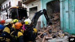 FILE - Firefighters clear debris from a building that partially collapsed inwardly, killing three people, in Havana, Cuba, Oct. 4, 2023.