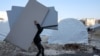 FILE - People receive mattresses distributed by an NGO, at a makeshift camp in the city of Afrin in the rebel-held part of Aleppo province, Syria, Feb. 16, 2023.