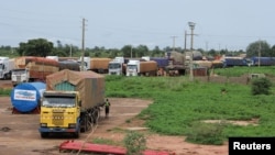 Trucks carrying food, humanitarian aid, and industrial equipment wait due to sanctions imposed by Niger's regional and international allies, in the border town of Malanville, Benin, Aug. 18, 2023.