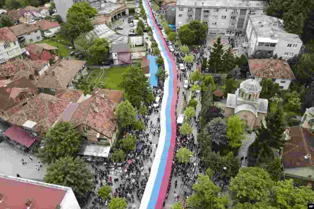 People hold a giant Serbian flag during a protest in the town of Zvecan, northern Kosovo.&nbsp;Hundreds of ethnic Serbs began gathering in front of the city hall in their repeated efforts to take over the offices of one of the municipalities where ethnic Albanian mayors took up their posts last week.