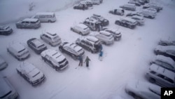 People stand in the parking area of the Alpine Base Area at Palisades Tahoe during a winter storm in Alpine Meadows, California, Feb. 24, 2023.