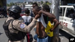 FILE - A police officer checks a man for weapons in Port-au-Prince, Haiti, May 11, 2024. 