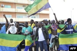 People holding Gabon national flags celebrate in Libreville on August 30, 2023. A group of Gabonese military officers appeared on television saying "all the institutions of the republic" had been dissolved, the election results canceled and the borders closed. (Photo by AFP)