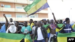 FILE - Residents holding Gabon national flags celebrate in Libreville on August 30, 2023 after a military officers appeared on television announced a coup after President Ali Bongo Ondimba's reelection. 
